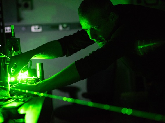Man working in a lab with green light in the background